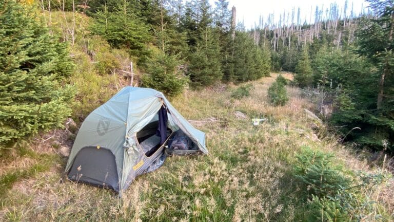 A one-person tent and campsite with gear for solo multi-day hiking