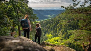 Two hikers standing on the Bildsteinfelsen looking into the Alb valley
