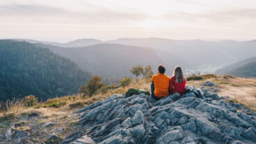 Two hikers sitting on the Scheibenfelsen looking into the valley near Bernau