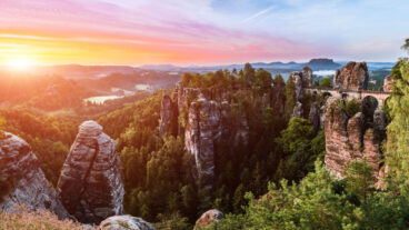 A view of the Bastei Bridge from the Ferdinand viewpoint with a sunrise over the Saxon Switzerland National Park