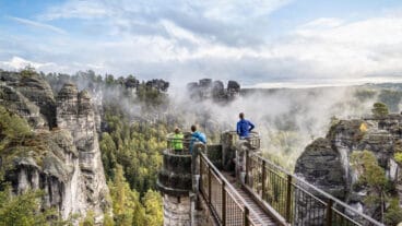 Hikers standing on a viewing platform on the Bastei Bridge in the Saxon Switzerland National Park