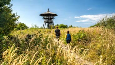 Two hikers walking toward the Eggeturm tower on the Preußischer Velmerstot