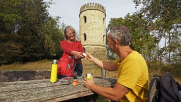 Two hikers pause at a rest area table in front of the Bierbaums Nagel