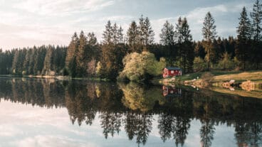 A cabin beside a mirror calm Ziegenberger Teich pond reflecting the landscape near Buntenbock