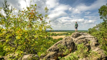 A hiker enjoys an impressive view over the Tecklenburger Land from the Dörenther Klippen